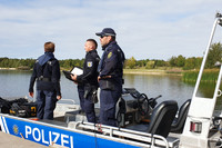 Drei Polizisten mit Uniform in einem Boot