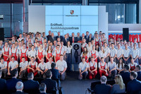 Eröffnung des neuen Porsche Ausbildungszentrums in Leipzig. Etliche Auszubildende in roten Latzhosen oder Anzughose und weißem T-Shirt posieren als Gruppe zusammen mit Vertretern der Chefetage von Porsche. 