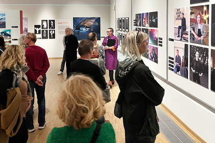 Mehrere Menschen schauen sich Fotografien im Ausstellungsraum an