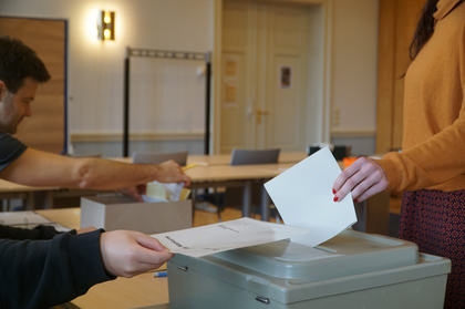 Eine Wählerin wirft im Wahllokal ihren Stimmzettel in eine Wahlurne ein.