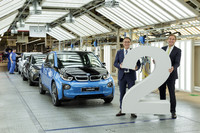 Oberbürgermeister Burkhard Jung und Hans-Peter Kemser von BMW halten eine mannsgroße 2 fest. Hinter ihnen stehen mehrere BMWs und zwei Werksmitarbeiter.