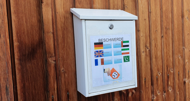 Ein Briefkasten auf dem "Beschwerde" in verschiedenen Sprachen steht.