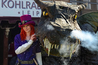 Ein Frau in einem Fantasykostüm steht neben einem Drachen, der Rauch aus der Nase pustet.