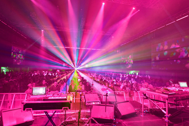 Tanzfläche mit viel Lichteffekten und Menschen vor einer Bühne