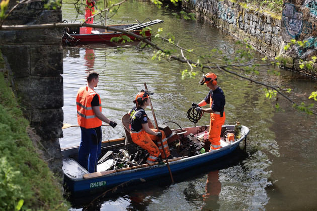 Drei Personen stehen auf einem Boot mit gesammelten Abfällen.