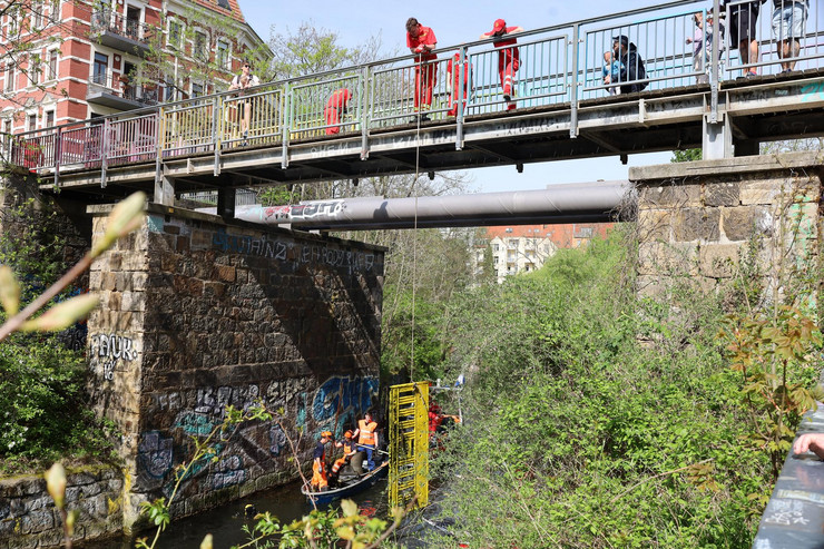 Mehrere Personen stehen auf einer Brücke und ziehen eine Warnbake auf dem Wasseer