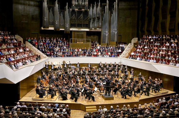 Das Orchester im großen Saal des Gewandhauses beim Spielen. Im Hintergrund die Orgel. Alle Plätze im Publikum sind besetzt.