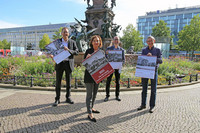 Drei Männer und eine Frau stehen vor einem Süringbrunnen und halten jeder einen Leipzig-Kalender in der Hand, bei dem jeweils eine andere Seite aufgeschlagen ist.