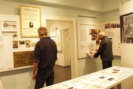 Zwei Männer schauen sich Tafeln und Fotos der Ausstellung im Schulmuseum Leipzig an.