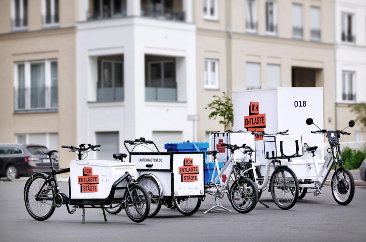 Auf einem Platz stehen verschiedene Arten von Lastenrädern mit der Aufschrift "Ich entlaste Städte".