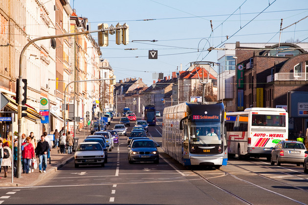 Georg-Schumann-Straße mit Straßenbahn, Autos und Fußgängern
