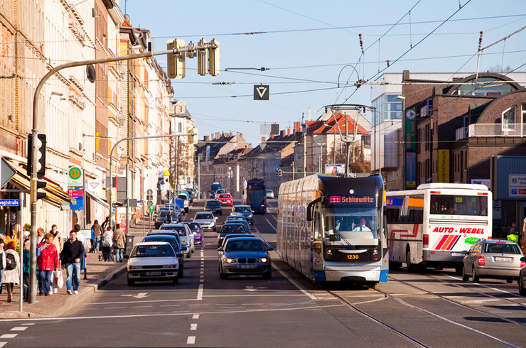 Georg-Schumann-Straße mit Straßenbahn, Autos und Fußgängern