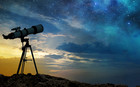 Ein Teleskop auf einem Felsen in der Abenddämmerung. Am Himmel sind bereits Sterne zu sehen.