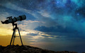 Ein Teleskop auf einem Felsen in der Abenddämmerung. Am Himmel sind bereits Sterne zu sehen.