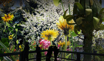 Besucher betrachten ein Gartenbild mit Blumen und einem blühenden Baum, das extrem vergrößert ist.