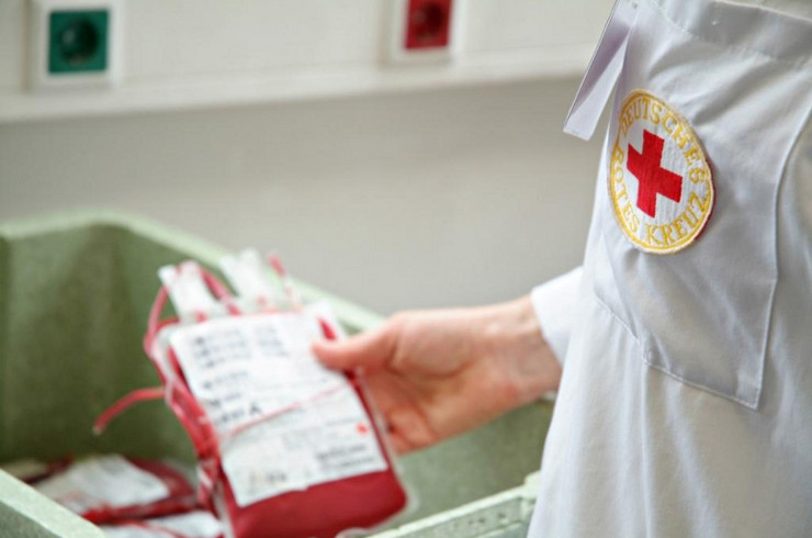 Person mit DRK-Logo auf dem Hemd hält Blutkonserve