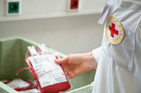 Person mit DRK-Logo auf dem Hemd hält Blutkonserve