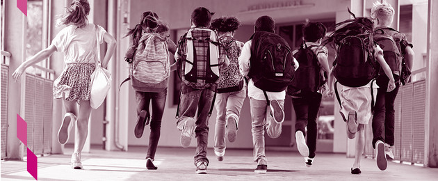Schulkinder rennen mit Ranzen auf dem Schulflur.
