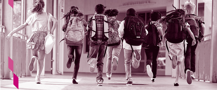 Schulkinder rennen mit Ranzen auf dem Schulflur.