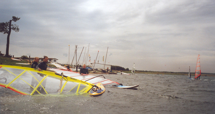 Windsurfer tragen ihr Surfbrett in den Cospudener See