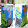 Abfallbehälter mit Graffiti-Motiv, ein Löwenzahn, ein Regenwurm sowie eine Spinne und ein Marienkäfer auf der Wiese