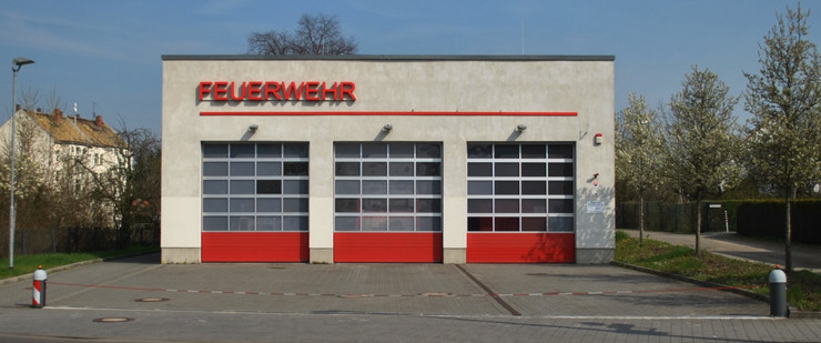 Das eingeschossige Gebäude der Freiwilligen Feuerwehr Mölkau mit Flachdach. Es besitzt drei große, rote Tore mit Fenstern.