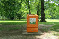 Orangene Blechbox in einem Park, die für Grillasche genutzt werden kann. 