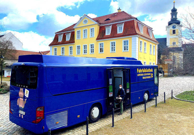 Im Vordergrund steht der Bus der Fahrbibliothek an der neuen Haltestellte in Stötteritz, im Hintergrund ist der Gutshof Stötteritz zu sehen
