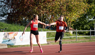 Olympische Athletin und paralympischer Athlet bei Staffelstabübergabe