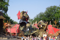 Klettergerüst in Form einen großen Drachens aus Holz mit vielen Kindern davor.