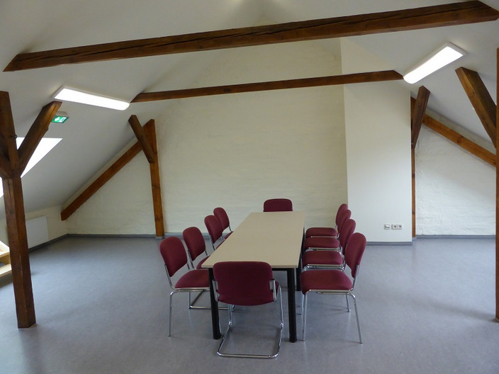 Raum mit Dachschrägen und einem Sitzungstisch in der Sporthalle Georg-Schumann-Straße 209
