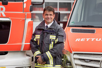 Axel Schuh steht in Feuerwehruniform vor zwei Feuerwehrautos