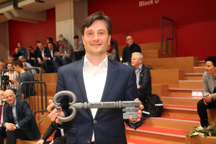 Bürgermeister Philipp Rosenthal hält symbolischen Schlüssel zur Eröffnung der Sporthalle Brüderstraße in der Hand