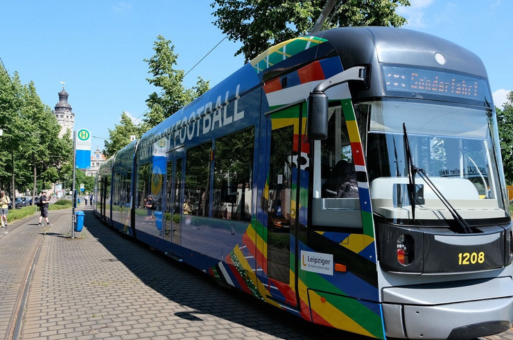 Eine Straßenbahn im Look der UEFA EURO 2024. Im Hintergrund ist das Neue Rathaus der Stadt Leipzig.