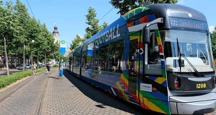 Eine Straßenbahn im Look der UEFA EURO 2024. Im Hintergrund ist das Neue Rathaus der Stadt Leipzig.