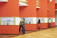 Vier Personen schauen sich in einer Ausstellung Objekte in Glasvitrinen an.