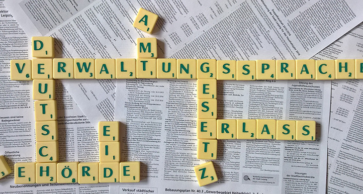 Scrabblebuchstaben liegen auf Bekanntmachungsseiten und formen die Wörter Verwaltungssprache, Deutsch, Bescheid, Amt und Erlass