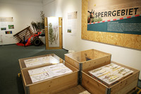 Blick in die Ausstellung mit verschiedenen Requisiten und Holzkisten mit Pflanzenpräparaten