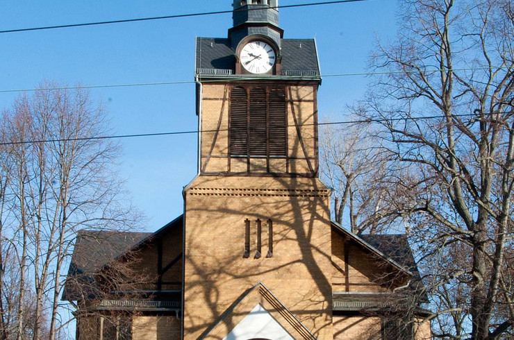 Eine Kirche mit Kirchturm und Uhr steht vor einem strahlend blauen Himmel