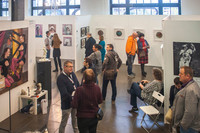 Besucherinnen und Besucher in den Ausstellungsräumen der Kunstmesse Leipzig. An den Wänden sind viele verschiedene Kunstwerke.