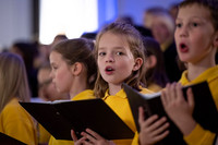Singende Kinder in gelben T-Shirts mit Liedheften