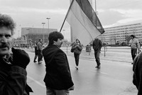Schwarz/Weiß Aufnahme aus dem Jahr 1990. Ein Mann steht auf einer Straße und hält die Fahne der BRD hoch. Im Hintergrund ist das Gewandhaus. Einige andere Menschen lauf um ihn herum.