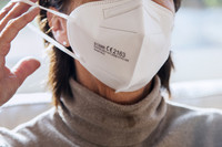 Eine Frau setzt sich eine FFP2-Maske auf.