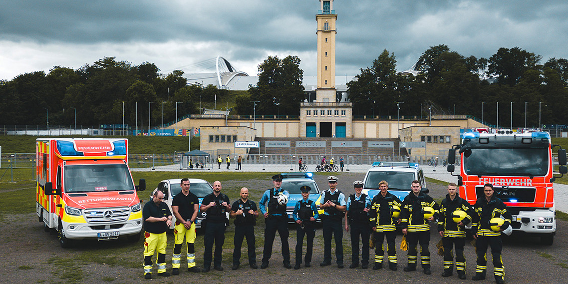 Einsatzkräfte von Polizei und Feuerwehr aufgereiht vor dem Stadion Leipzig