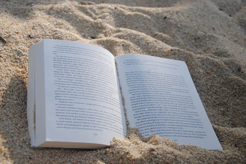 Ein aufgeschlagenes Buch im Sand