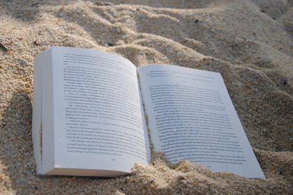 Ein aufgeschlagenes Buch im Sand