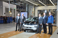 Elektroauto steht in Fabrikhalle. BMW-Chefs und Politiker stehen daneben.