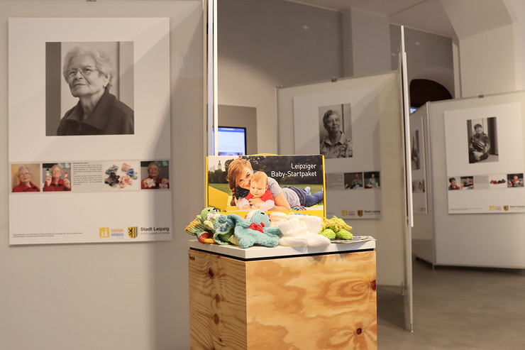 Eine Ausstellung im Stadtbüro, in der Seniorinnen vorgestellt werden, die Babyschuhe für das Leipziger Starterpaket stricken.
