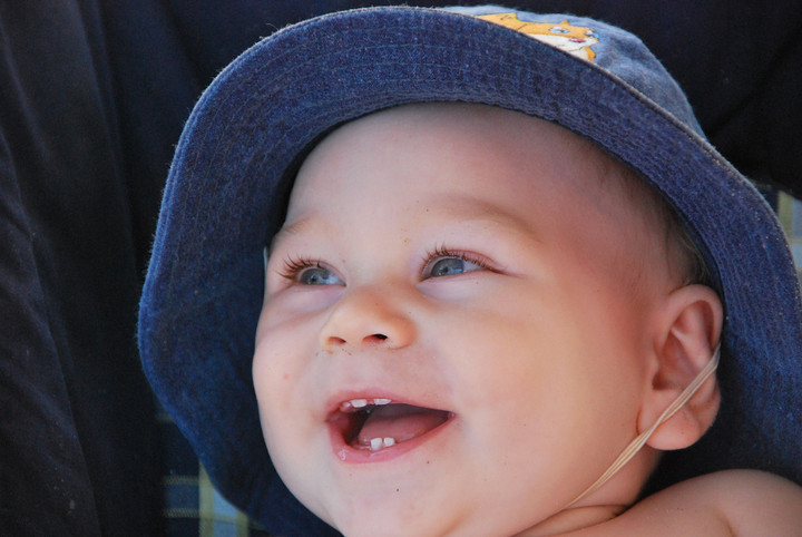 lachendes Baby mit blauer Sonnenmütze