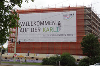 Schriftzug "Willkommen auf der Karli" schwarz auf weißem Grund hängt an Gebäude